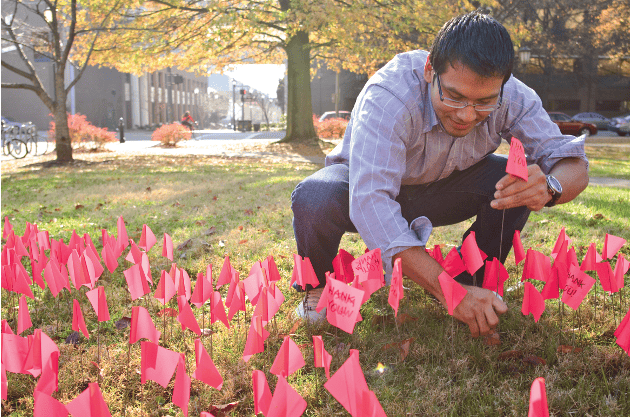 William Hernandez of La Unida Latina Lambda Upsilon Lambda Fraternity Inc. plants flags on the Harris Hall lawn. The fraternity is sponsoring an informational event with three other student groups on Dec. 4 at the Student Commons to help educate the VCU community on HIV and AIDS in honor of World AIDS Day.